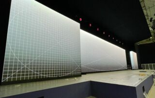 Eine Unilumin-LED-Wand auf einer Bühne installiert. Die dreiteilige Wand, deren mittlerer Teil den Hauptfokus des Bühnenbilds bildet, zeigt Testbilder, die während des Aufbaus zur Kalibrierung dienen.